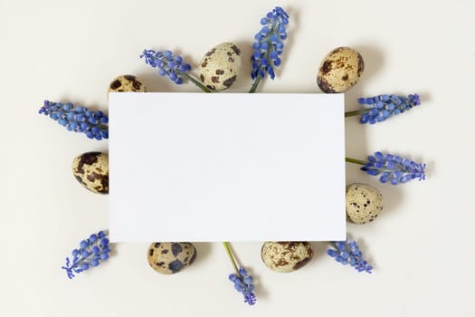 Easter composition with paper blank quail eggs and fresh flowers.Top view, flat lay, copy space