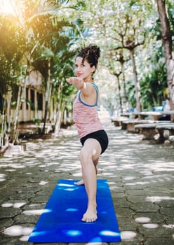 Young woman doing yoga virabhadrasana II outdoors. Girl practicing yoga Warrior II pose outdoors. Latin woman doing yoga warrior pose outdoors.