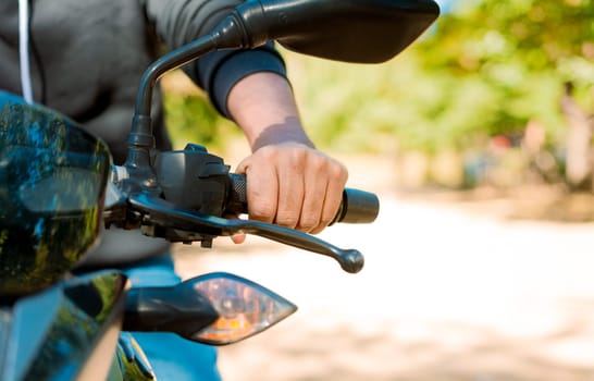 Close up of the hands on the handlebars of a motorcycle. Hands of a person on the motorcycle handlebars. Motorbike speeding concept, Hands of a motorcyclist on the handlebars