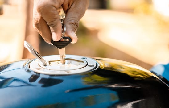 Hand opening the gas tank of the motorcycle, Motorcyclist opening the gas tank of the motorcycle. Hands opening the gas tank of the motorcycle with the key