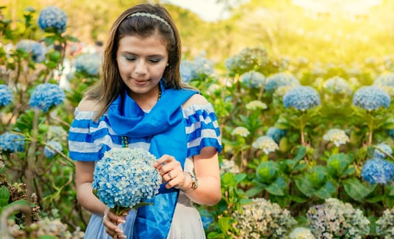 Nicaraguan girl in traditional folk costume holding flowers in a nursery. Beautiful Nicaraguan woman in national folk costume holding flowers in a nursery. Nicaraguan folk costume