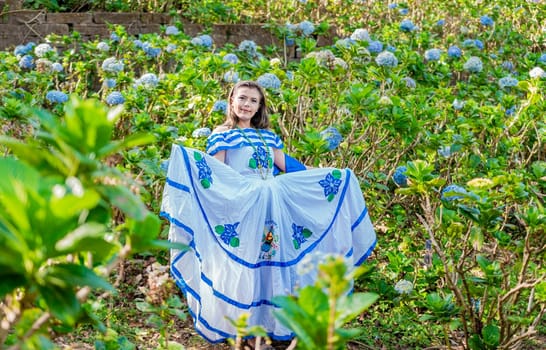 Portrait of young Nicaraguan woman in traditional folk costume in a field of flowers, Nicaraguan woman in traditional folk costume in a field of flowers