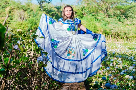 Nicaraguan woman in traditional folk costume in a field of Milflores, Smiling woman in national folk costume in a field surrounded by flowers. People in Nicaraguan national folk costume
