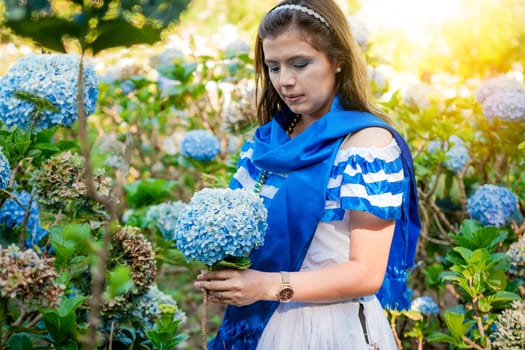 Woman in traditional Central American folk costume holding flowers in a nursery. Beautiful woman in national folk costume holding flowers in a nursery. Nicaraguan folk costume