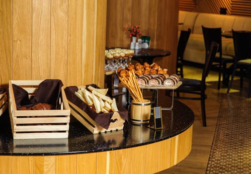 A buffet table with variety of bread in the wooden baskets