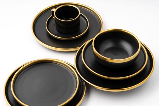 A set of black and golden ceramic plates and cup on a white background