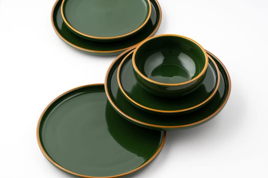 A set of green ceramic plates and bowl on a white background