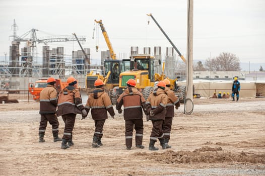 A beautiful shot of workers in special equipment and helmets with oil and gas construction in the background