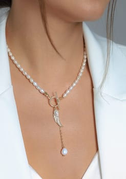 A closeup shot of a key pearl necklace worn by a Caucasian female