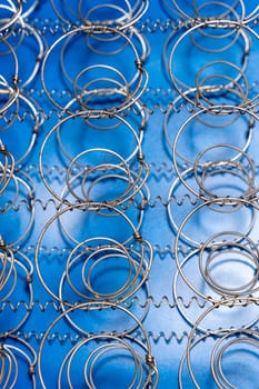 Abstract background The internal structure of a spring mattress. close-up of an old spring mattress on a blue background. Spring block. Sofa and bed. defocusing. top view