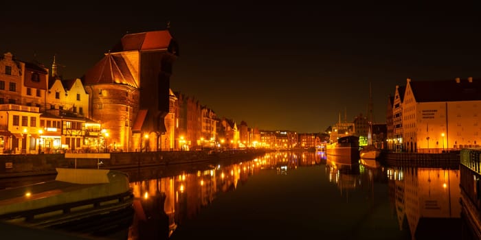 Old town in Gdansk at night. The riverside on Granary Island reflection in Moltawa River Cityscape at twilight. Ancient crane at dusk. Visit Gdansk Poland Travel destination. Tourist attraction