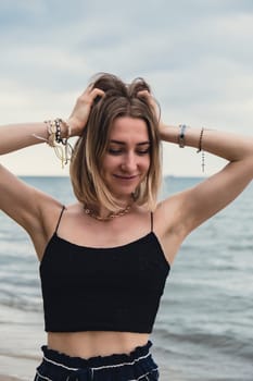 Young woman standing on blurred beachside background. Attractive female enjoying walking the sea shore. travel and active lifestyle concept. Springtime. Relaxation, youth, love, lifestyle solitude with nature. Wellness wellbeing mental health inner peace Slow life digital detox