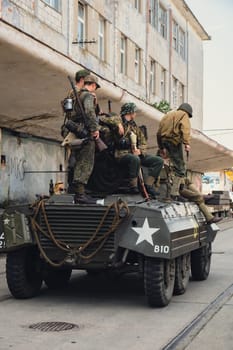 Hel, Poland - August 2022 Military troops marching during 3 May Polish Constitution Day ceremonial patriotic parade. Polish armed forces tanker military parade. Old guns and cars. Feast of Polish Armed Forces Day, American soldiers with US flag on parade Nato Vehicles Military Equipment