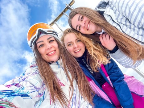 Group of happy friends skier taking selfie hiking mountains. Girls smiling Makes Selfie In Ski Clothing On Snow Mountain. Resting relaxing extreme recreation active lifestyle activity technology smart phone mobility internet online concept. Emotions nature on background.