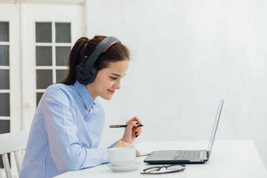 woman in headphones talks on Skype writes in a notebook Internet remote work online communication