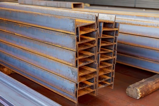 The stack of rolled metal is on the background of a green field, facing the steel profile. Various products from a metal of a channel.