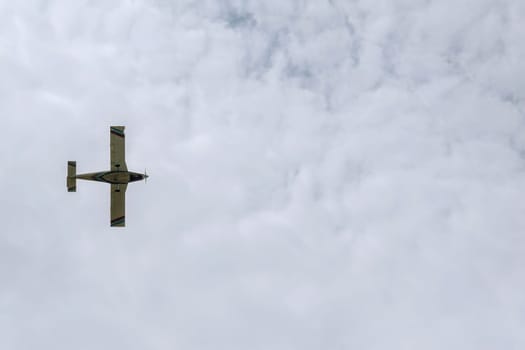 A small first-class plane flies in the cloudy sky. View from below. Horizontal orientation.