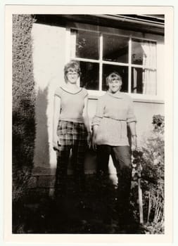 THE CZECHOSLOVAK SOCIALIST REPUBLIC - CIRCA 1980s: Vintage photo shows young girls in front of country house. Retro black and white photography.