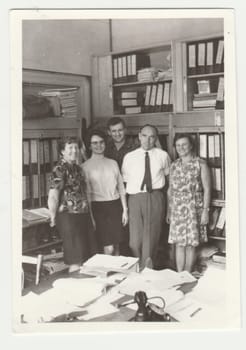 THE CZECHOSLOVAK SOCIALIST REPUBLIC - CIRCA 1980s: Vintage photo shows people - colleagues pose in the retro office. Retro black and white photography. Circa 1980s.