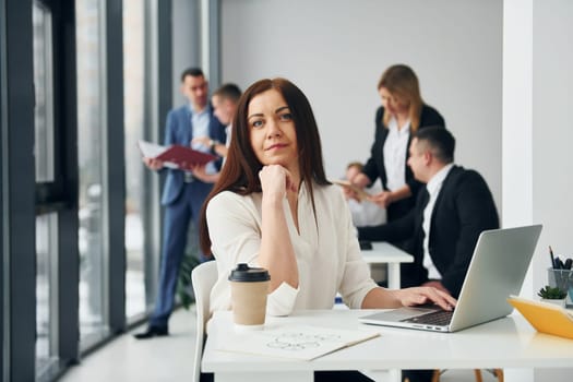 Woman in front of her colleagues. Group of people in official formal clothes that is indoors in the office.