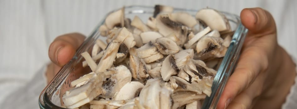 Unrecognizable woman showing into camera frozen food sliced mushrooms champignon homemade. Harvesting concept. Stocking up vegetables for winter storage Healthy food, Cooking ingredients