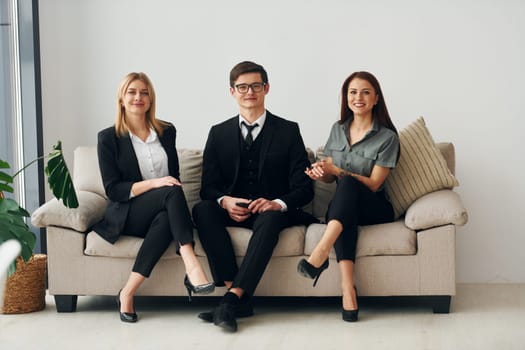 Young guy and two women in formal official clothes together indoors.