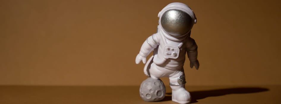 Plastic toy figure astronaut on beige neutral background Copy space. Concept of out of earth travel, private spaceman commercial flights. Space missions and Sustainability