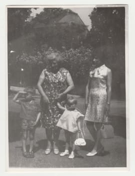 THE CZECHOSLOVAK SOCIALIST REPUBLIC - CIRCA 1970s: Vintage photo shows mother and grandmother with children outdoors. Retro black and white photography. Circa 1970s.