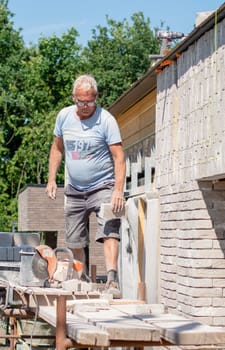 the bricklayer makes the facade of the house from gray bricks with cement and plaster at the construction site. High quality photo