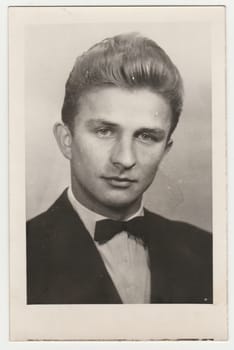 THE CZECHOSLOVAK SOCIALIST REPUBLIC - DECEMBER 20, 1961: Vintage photo shows a young man. He wears black jacket and bow tie. Studio portrait. Retro black and white photography. Circa 1960s.