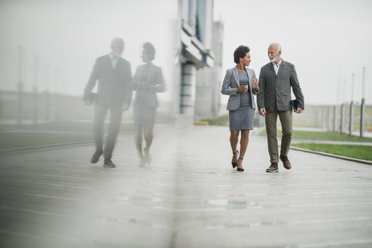 Shot of two successful multi-ethnic business people talking while walking during a coffee break in front of the office building.
