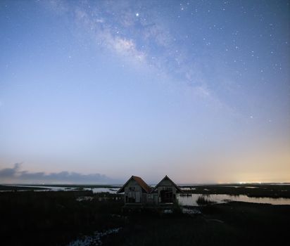 Milky Way early morning before sunrise, old abandoned house, red roof on open field
