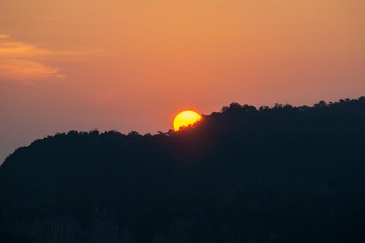 Sunrise behind the mountains, the shadows of the mountains, the orange sky with faint clouds.