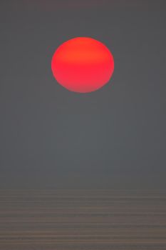 The sun is falling into the sea. It is colour orang The sky and the sea is dark