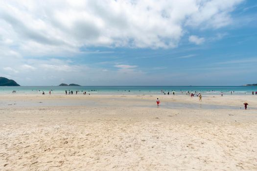 People take a dip in the sea and stroll on the white sand.