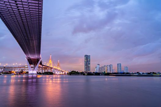 Purple led light under the bridge over the river On a cloudy day in the sky. Bhumibol Bridge, Samut Prakan, Thailand