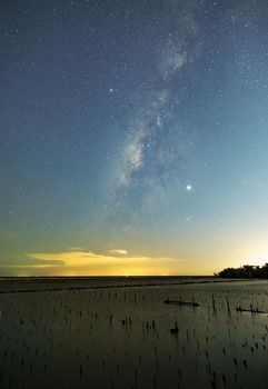 The Milky Way on the night sky with the light reflected from the city lights. The Mangrove forests that only stump. The sea of ​​Samut Sakhon.