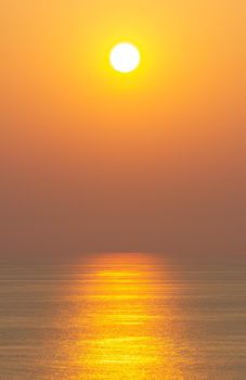 The sunset, the sea surface reflects the sunlight in gold. Clear sky, orange without clouds