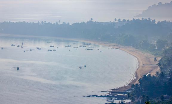 Shallow fishing boats anchor at the beach on thick fog days.	