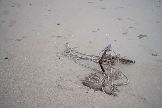 A small anchor rusted on the sand Of the beach by the sea	