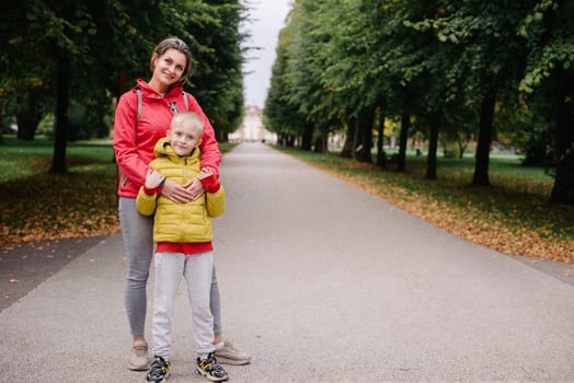 mother and son stand hugging in the park in the fall. happy mother playing with her son in the park. Mother hugs her son while standing in the forest in autumn.