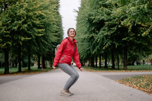 Young caucasian woman girl with toothy smile jumping in park forest outdoors looking at camera.