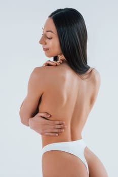 Rear view. Woman with sportive slim body type in underwear that is in the studio.