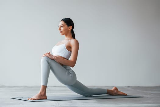 Doing yoga exercises. Woman with sportive slim body type in underwear that is in the studio.