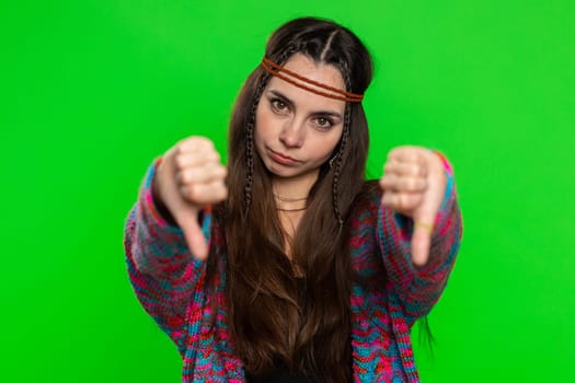 Dislike. Upset unhappy young woman showing thumbs down sign gesture, expressing discontent, disapproval, dissatisfied, dislike. Pretty hippie girl. Indoors shot on chroma key background, green screen