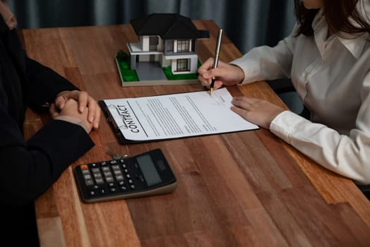 Completing the final step of the house loan process, the buyer signs the loan contract paper with a pen on the desk, securing the ownership of the property. Enthusiastic