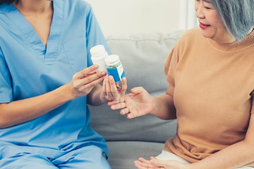 Caregiver advising contented senior woman on medication in the living room. Medication for seniors, nursing house, healthcare at home.