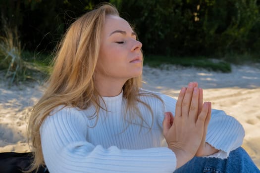 Young woman meditate on beach next to sea ocean. Breath exercises wellbeing for mental health. Breathing therapy. Balance kundalini energy every day routine practice good for woman health mindfulness. Healthy female enjoy outdoor lifestyle relaxation exercise and meditation on beach vacation