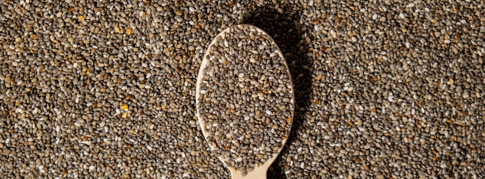 Chia seeds in wooden spoon. Healthy superfood rich in Omega 3 fatty acids. Dry healthy natural ingredient. Chia grains are falling. Vegetarian food