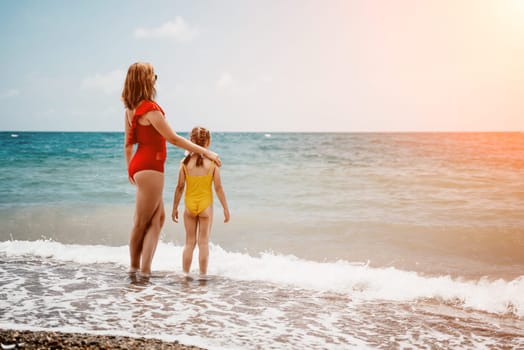 Happy loving family mother and daughter having fun together on the beach. Mum playing with her kid in holiday vacation next to the ocean - Family lifestyle and love concept.